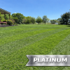 Platinum LCP Promotion 20 Off 1 - Grasshopper Gardens Expansive green lawn with a wooden porch on the left and a large silver Platinum sign in the foreground.
